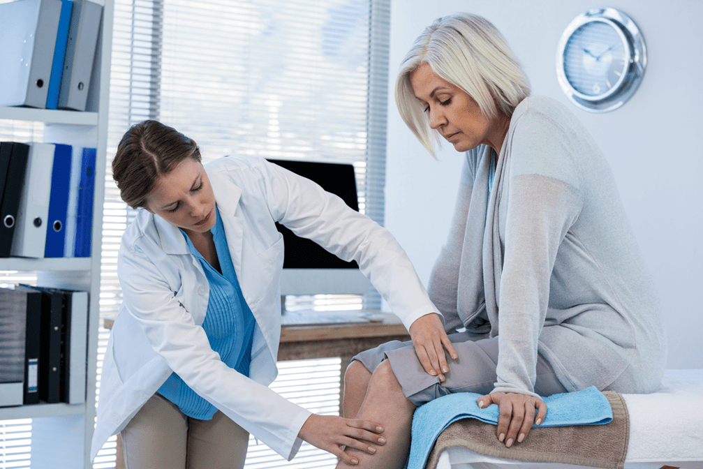 The doctor examines a patient with osteoarthritis of the knee joint. 
